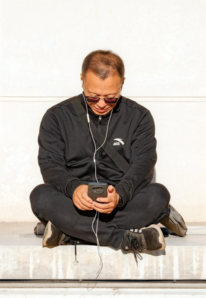 猫背で携帯を触っている男性